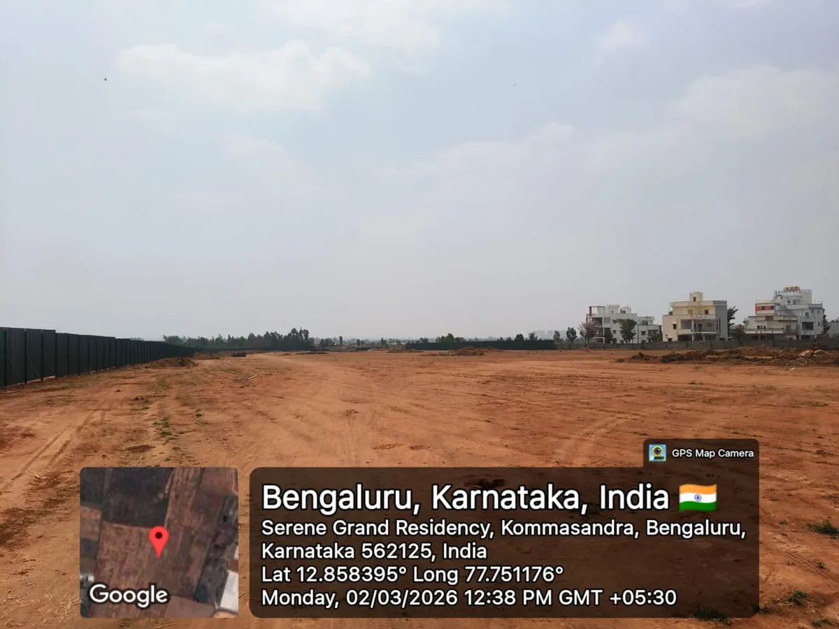 Godrej Regent Park cleared project land bordered by green hoarding with neighbouring homes alongside, Kada Agrahara, Sarjapur — March 2026 (Karnataka RERA filing)