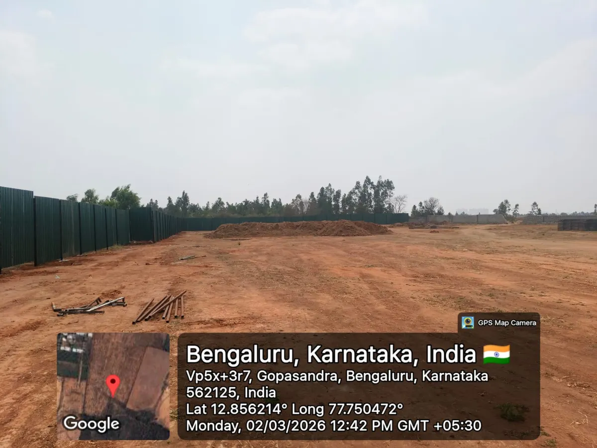 Godrej Regent Park cleared land with green boundary hoarding, an excavated soil mound and staged steel, Kada Agrahara — March 2026 (Karnataka RERA filing)