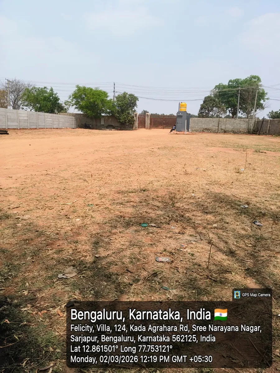 Godrej Regent Park cleared project land with the compound wall and site entrance in the distance, Kada Agrahara, Sarjapur — March 2026 (Karnataka RERA filing)